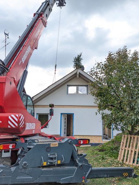Kran hebt den Richtkranz auf das fertig montierte Holzständerhaus – Richtfest bei HT Scherer BAUprojekt