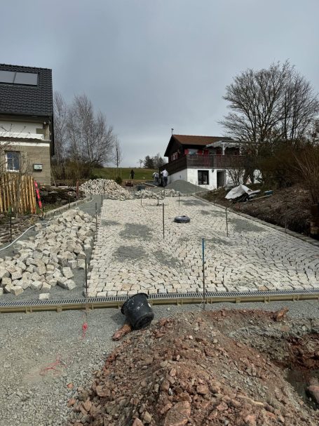„Abgezogene Pflasterfläche mit verlegten Naturstein-Granitpflasterreihen“