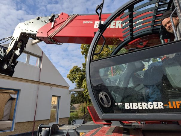 Kran hebt Wandelement eines Holzständerhauses auf die Baustelle – präziser Aufbau durch HT Scherer BAUprojekt