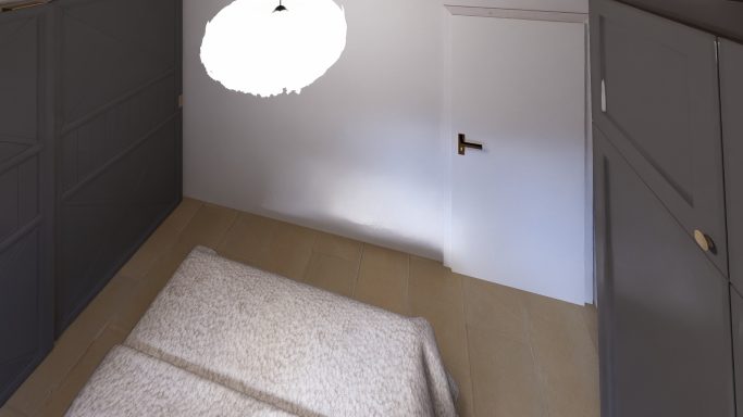 Helle, minimalistische Zimmeransicht mit weißen Wänden und einem großen Bett.