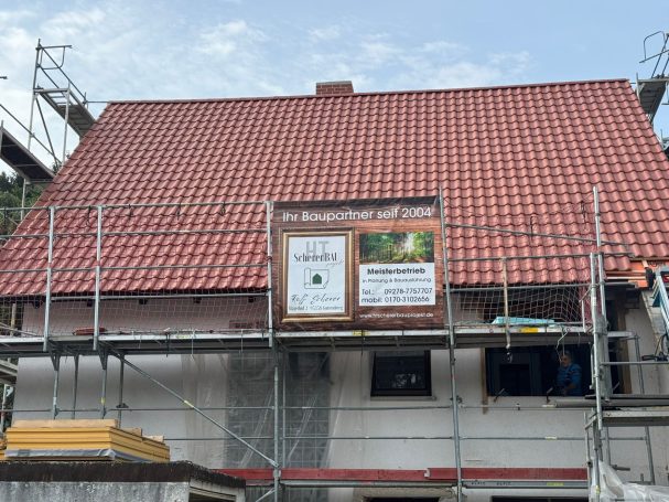 Hausansicht mit neuem Dach und Werbebanner von HT Scherer BAUprojekt, die das Dach saniert haben. 