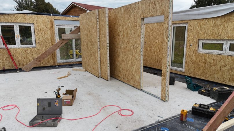 Montage der ersten Holzständerwände auf der Bodenplatte – Aufbauphase eines Einfamilienhauses in Holzbauweise