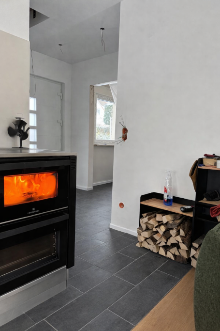 Gemütlicher Wohnraum mit Ofen, Holzlager und moderner Innenausstattung.
