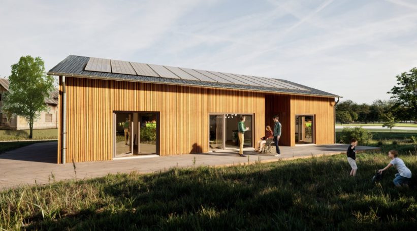 Einfamilienhaus aus Holz mit Solarpanelen, umgeben von grüner Landschaft und Menschen im Garten.