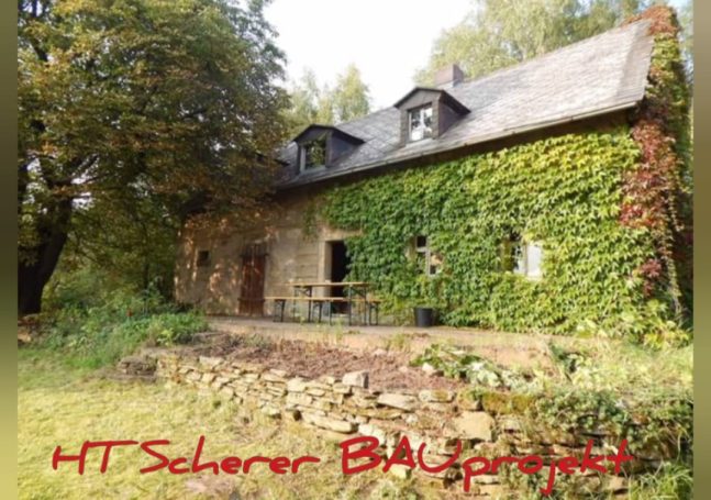 Ehemaliges Haus mit begrüntem Mauerwerk und einem kleinen Garten.