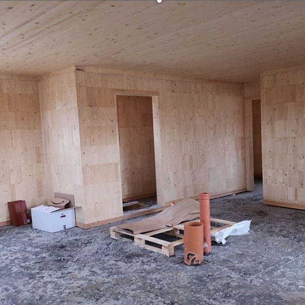 Traditioneller Vollholzbau mit Blockbohlenkonstruktion, steilem Satteldach und Naturstein-Elementen – ökologisches Bauen mit regionalem Hand