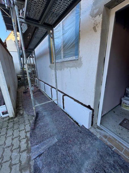 Baugerüst neben einer Wand, die renoviert wird, mit offenem Zugangstürbereich.