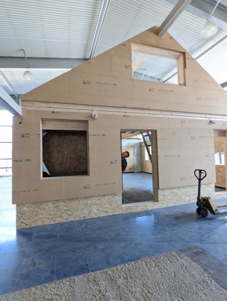 Ralf Scherer schaut aus dem Holzrohbau seines Holzständerhauses aus der Türe heraus.
