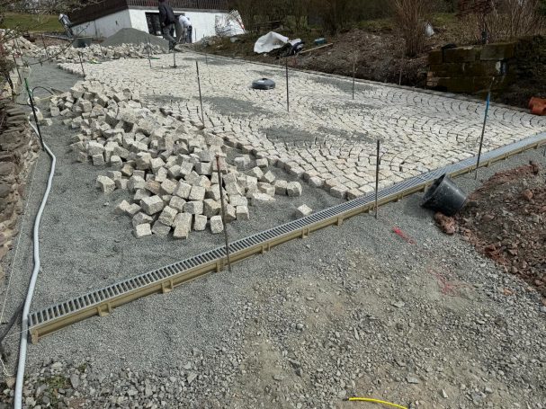 „Granitsteinfläche mit Pflasterarbeiten und eingelassener Entwässerungsrinne“