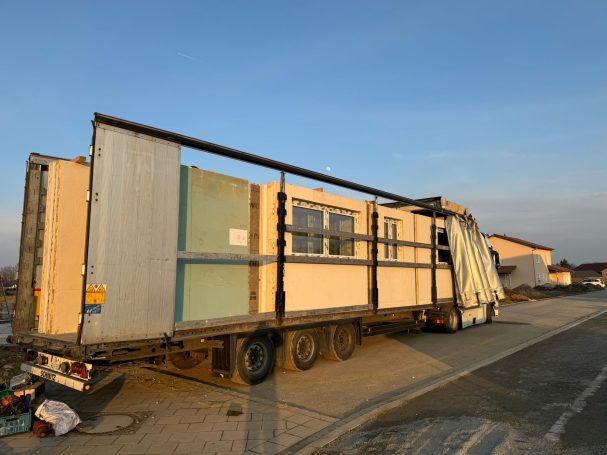 Baucontainer auf einem Lkw, teilweise offen, mit blauen und grauen Wänden.