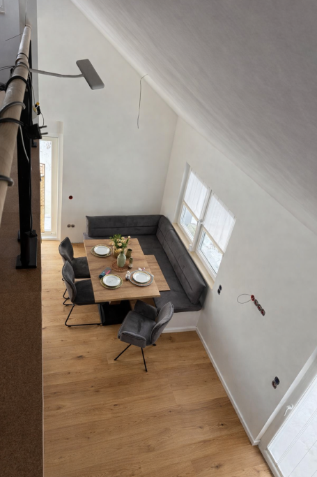 Helles Esszimmer mit grauem Tisch, Stühlen und Fensterlicht.