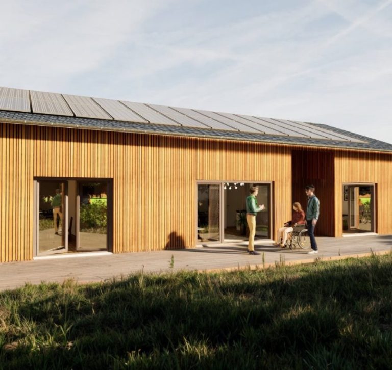 Holzhaus mit Solarpanelen, umgeben von Wiese und drei Personen davor.