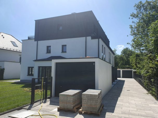 Modernes, zweigeschossiges Wohnhaus mit Garagen und gepflegtem Garten.