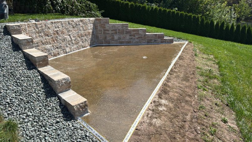 Baugrube mit neu errichteter Stützmauer und vorbereiteter Bodenplatte – Bauprojekt von HT Scherer BAUprojekt