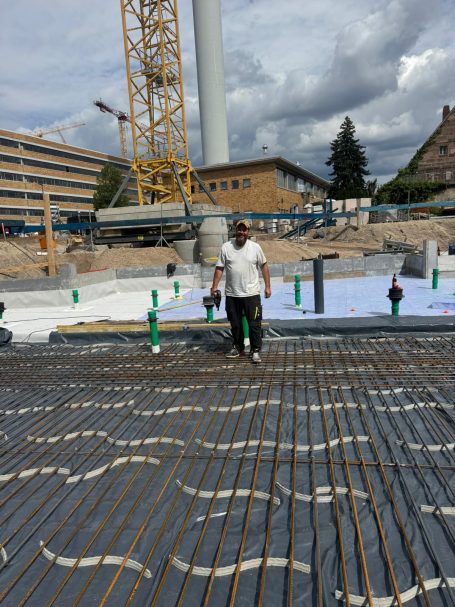 Ralf Scherer auf Großbaustelle mit verlegter Stahlbewehrung und sichtbarer Rohinstallation – Vorbereitung für Bodenplatte 