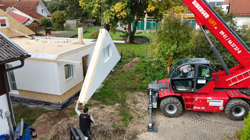 Anheben und Positionieren einer Holzständerwand mit Teleskoplader – Aufbauarbeiten auf der Baustelle in Bayern